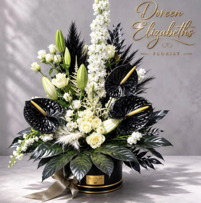 Cruella - featuring a luxurious combination of creamy white roses, elegant white lillies, delicate white blooms and glossy black anthuriums, this arrangement brings together timeless beauty and contemporary sophistication. accented with dramatic dark foliage, contrasting textures and elegant finishing touches, every detail creates a look that is both glamorous and unforgettable.